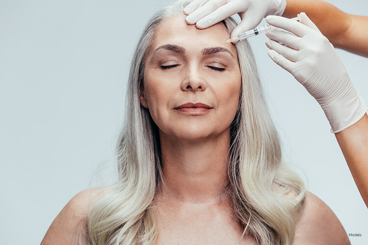 Mature woman getting an injection on her forehead